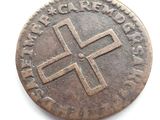 an old coin with a cross on it sitting on a white surface