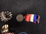 a silver medal, a silver ring, and a red, white, and blue ribbon laying on a black surface