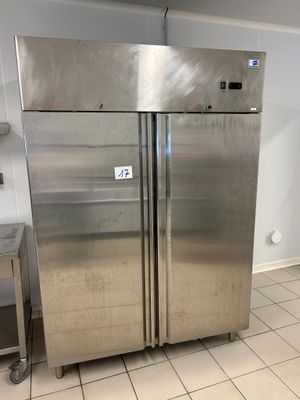 two stainless steel refrigerators in a kitchen with tile flooring