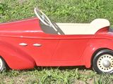 a red toy car sitting in the grass on the ground
