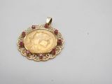 a gold coin pendant with ruby stones on a white surface