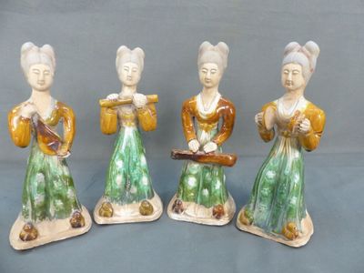 three ceramic figurines of women with musical instruments on a blue background