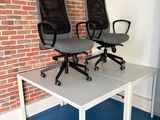 deux chaises de bureau posées sur une table devant un mur de briques