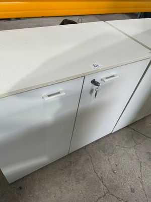 une armoire blanche posée par terre à côté d'un camion jaune