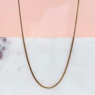 a close up of a gold chain on a marble surface