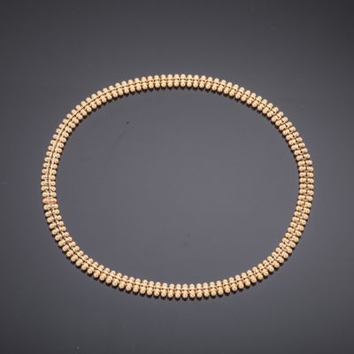a gold beaded necklace on a black background