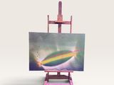 un petit chevalet sur lequel est accrochée une peinture représentant un arc-en-ciel