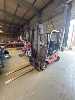 a forklift in a warehouse with other vehicles in the background