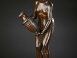 a bronze statue of a woman holding a vase on top of a marble base