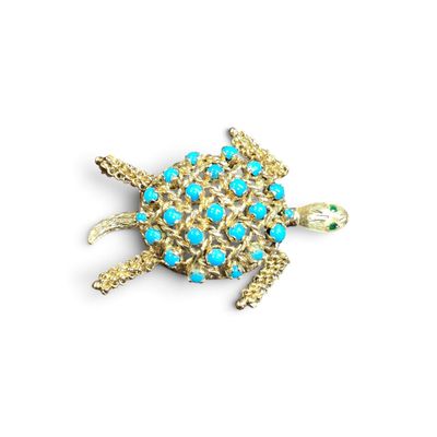 un gros plan d'une broche en forme de tortue ornée de pierres turquoise