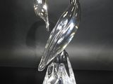 une figurine de cygne en verre transparent posée sur une table noire
