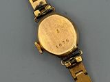 an image of a gold wrist watch on a gray surface