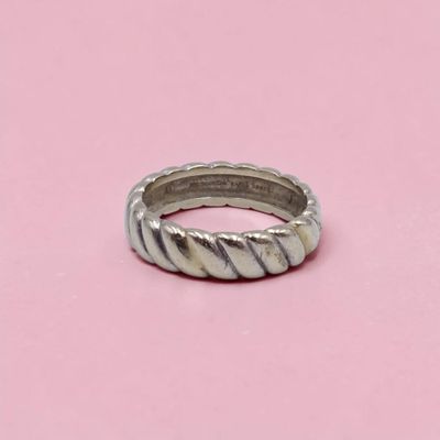 un gros plan d'une bague en argent posée sur une surface rose