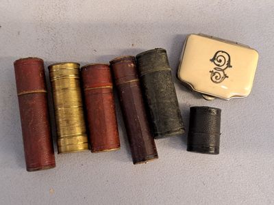 Plusieurs vieux livres sont alignés sur une table, à côté d'un briquet.