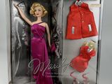 La poupée Barbie porte une robe rouge et un manteau rouge.