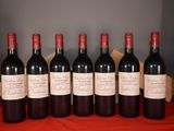 six bottles of red wine are lined up on a table