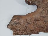 a wooden sculpture of a bird on a white surface
