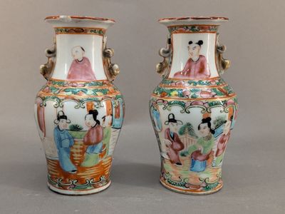 pair of chinese vases with figures on them sitting on a table