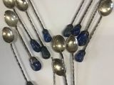 six silver spoons with blue handles and chains on a white surface