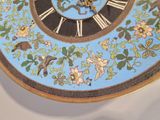a clock that has a bird and flowers on it