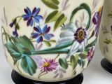 two vases with flowers painted on them sitting on a table