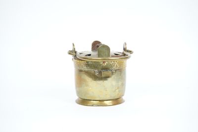 an old brass pot with a coin inside of it on a white surface