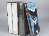 three books are stacked on top of each other on a gray surface