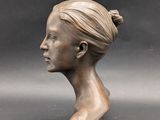 a bronze bust of a woman with a bun on her head