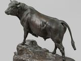 statue of a bull standing on a rock on a gray background