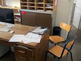 a desk with a computer and a chair in a room