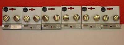 Quatre types différents d'interrupteurs électriques sont alignés contre un mur rouge