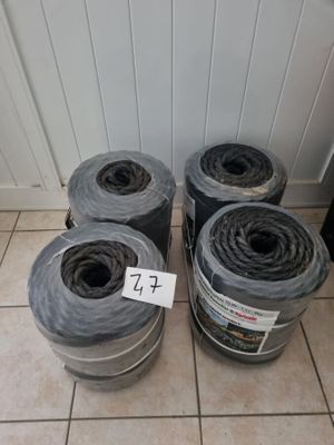 quatre rouleaux de plastique noir sont posés par terre les uns à côté des autres