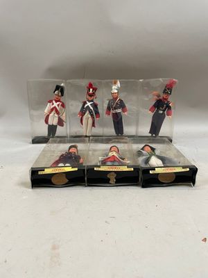 quatre petits soldats en plastique sont exposés dans une vitrine posée sur une surface blanche