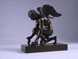 statue of a boy kneeling on a base with wings on his head