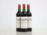 three bottles of red wine sitting on top of a white table