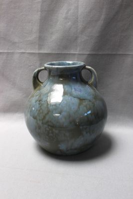 un vase bleu posé sur une table blanche