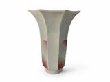 a white and red vase sitting on a white surface
