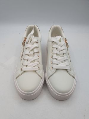 les baskets blanches sont posées sur une surface blanche, devant un fond blanc