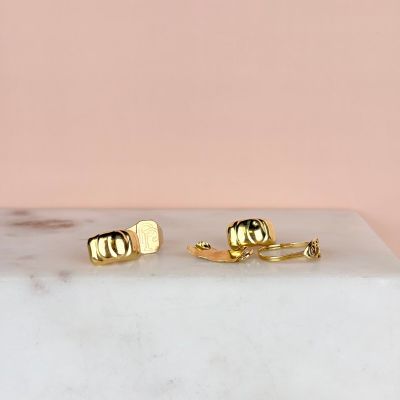 a pair of gold stud earrings sitting on top of a marble slab