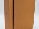 an old book with a brown cover sitting on top of a white surface