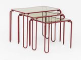 a set of three red metal nesting tables with glass tops