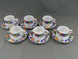 six tasses et soucoupes ornées de motifs colorés, posées sur une table