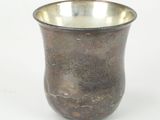 a silver cup with a design on it on a white surface