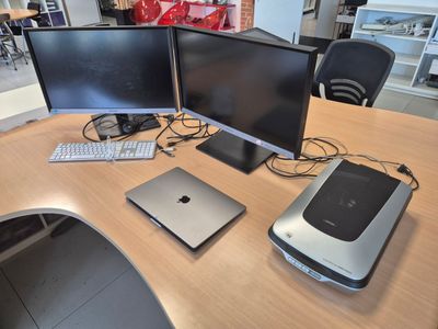 three computer monitors and a laptop on a desk