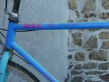 un vélo bleu appuyé contre un mur de pierre