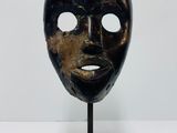 an image of a wooden mask on a stand on a white surface