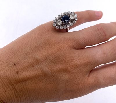la main d'une femme tenant une bague sertie d'un diamant et d'un saphir