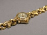 a gold bracelet with a watch on it on a table