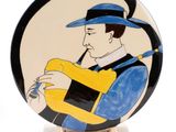 a picture of a decorative plate with a man playing a guitar