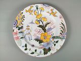 une assiette décorée de fleurs et d'oiseaux, posée sur une table